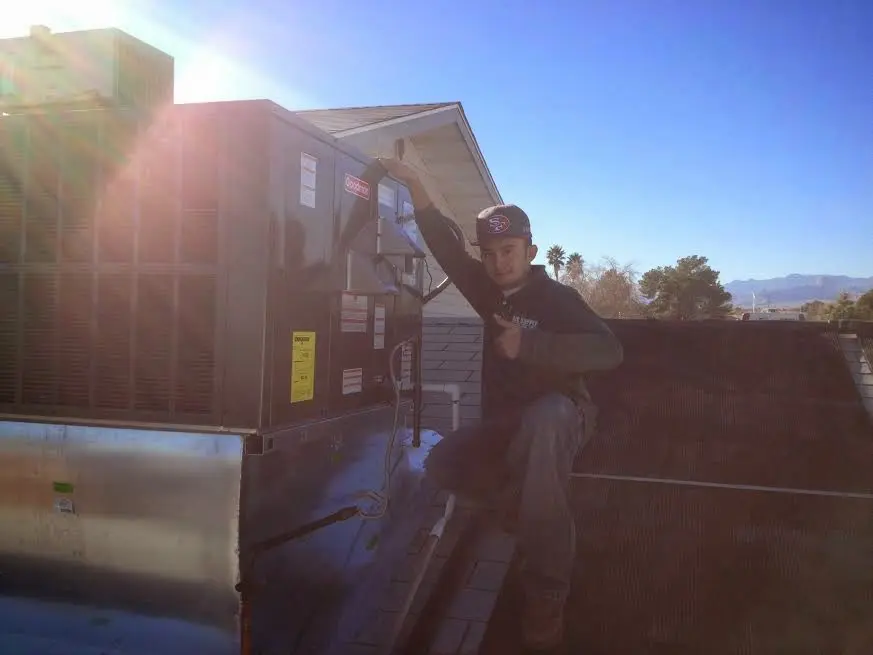 HVAC technician performing AC Tune-Up on a rooftop unit in Fresno